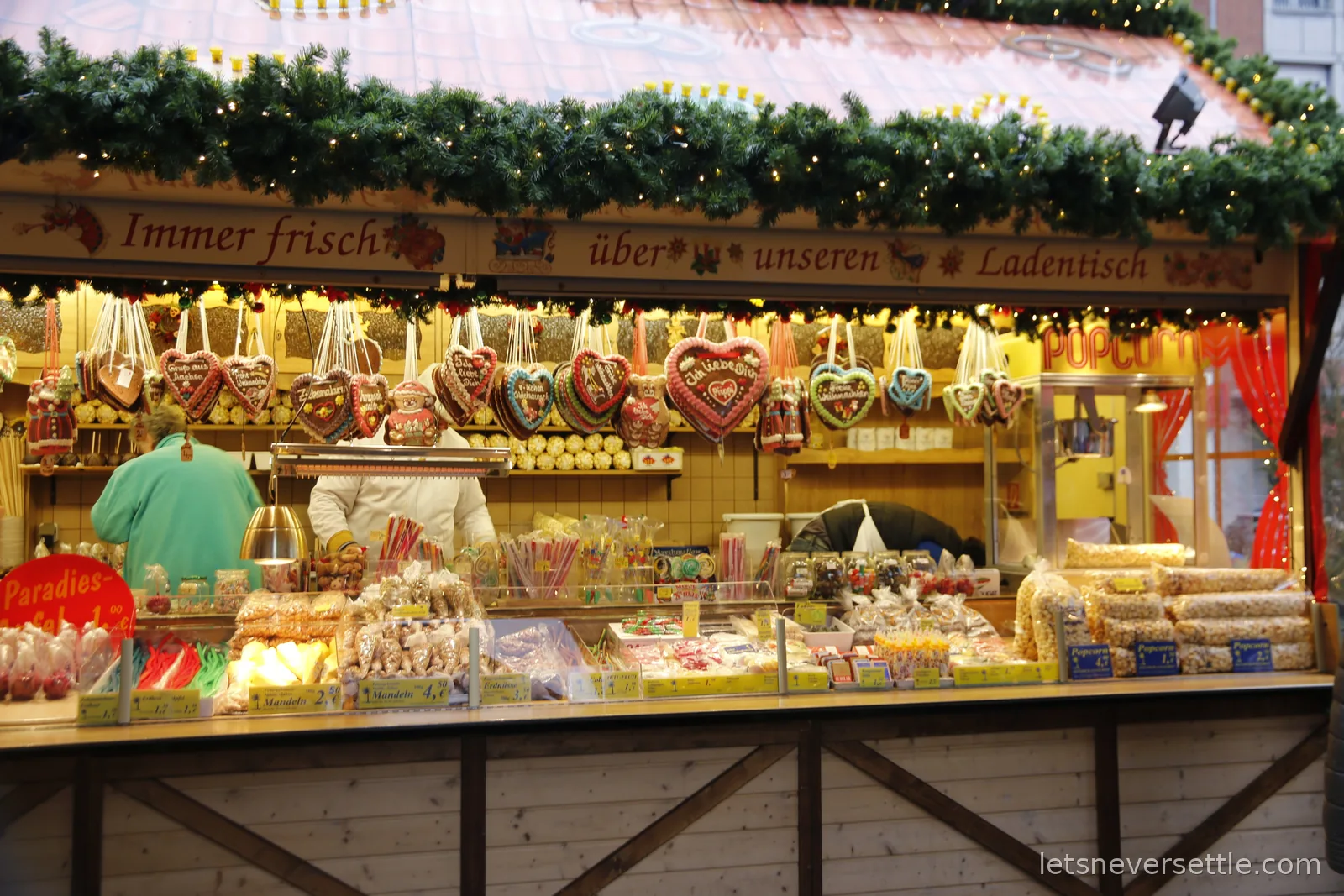 Christmas market sweet stall hung with rows of decorated gingerbread hearts, with popcorn and candied nuts on the counter below