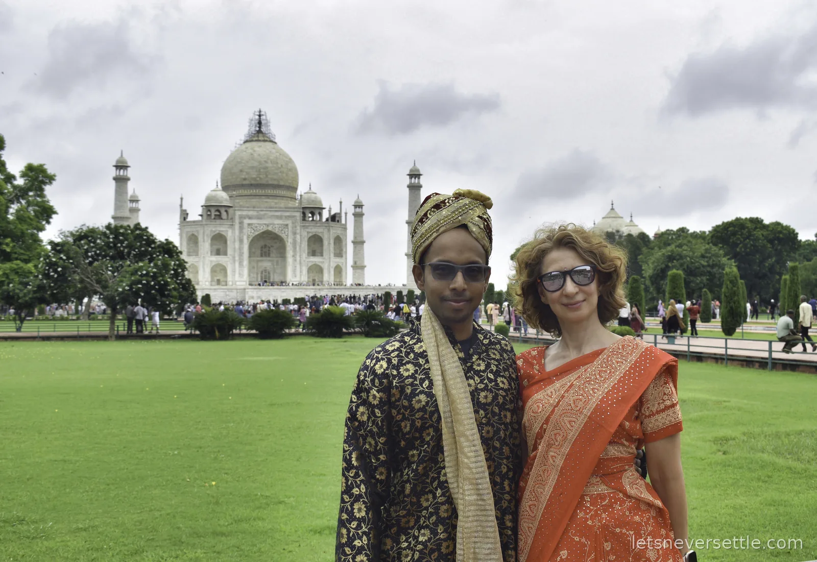 Dileep in a dark embroidered kurta and turban and Inga in an orange sari standing on the lawn in front of the Taj Mahal