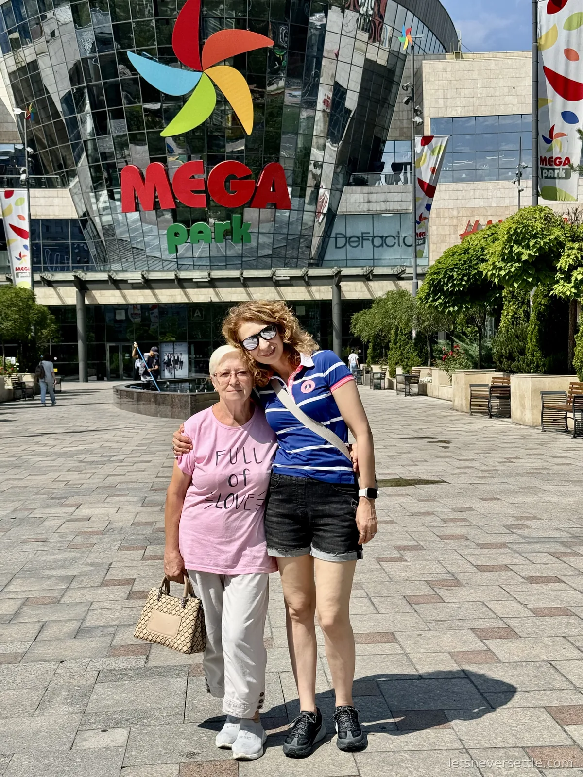 Inga with her arm around an older woman in a pink Full of Love t-shirt outside the MEGA Park shopping centre in Almaty