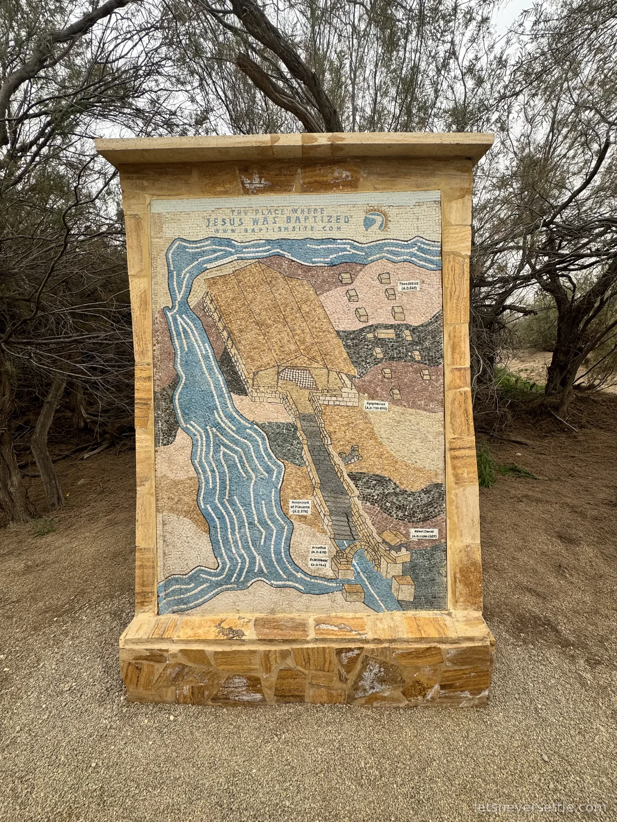 A large mosaic panel in a stone frame at Bethany Beyond the Jordan, mapping the baptism site along the River Jordan under the heading The Place Where Jesus Was Baptized