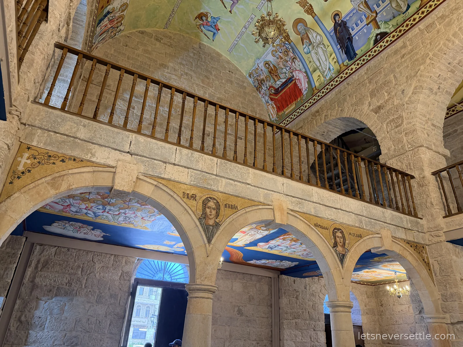 Inside St George's Church in Madaba, looking up at the wooden gallery, the stone arcade and the painted vaults above
