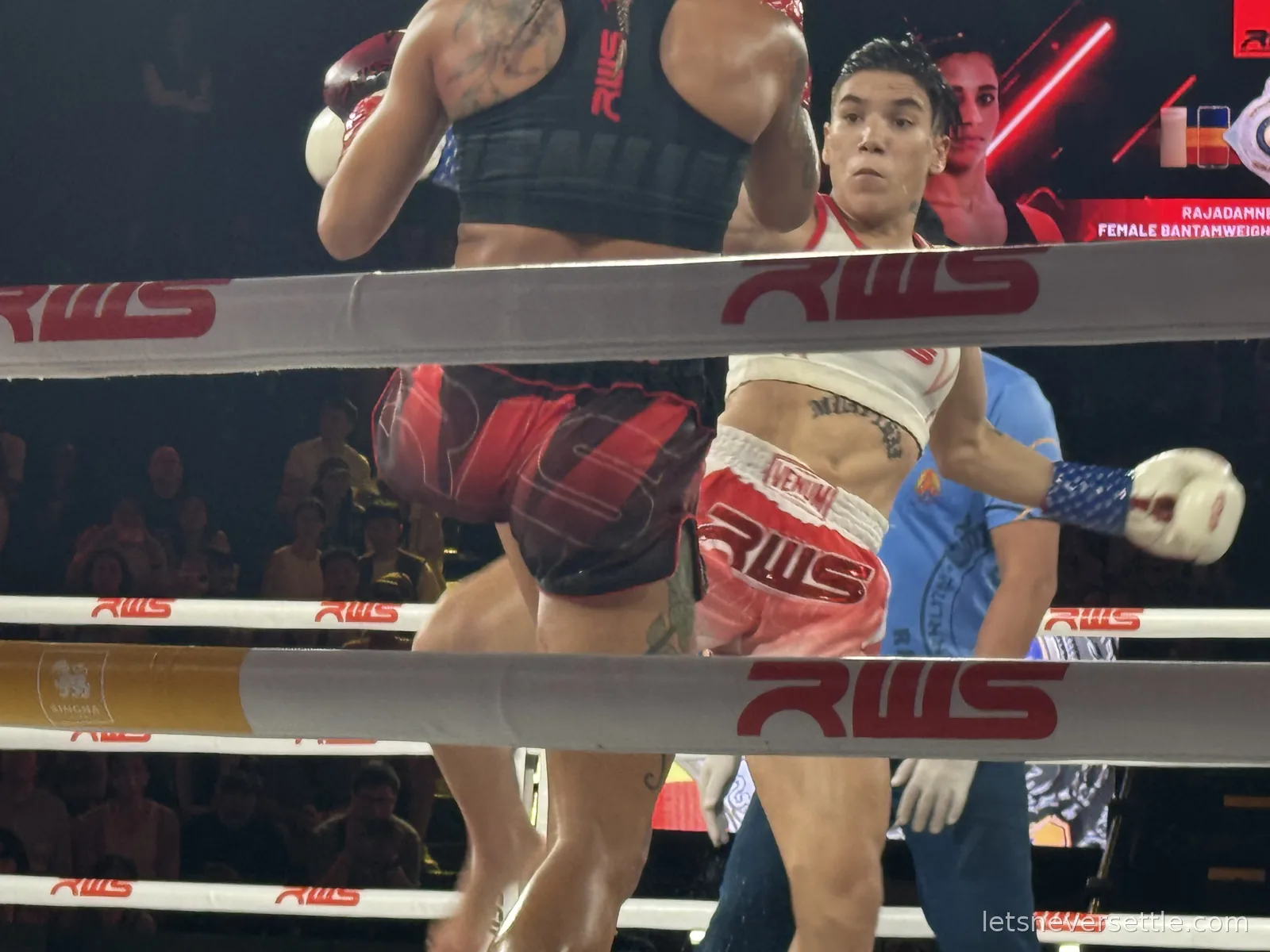 Two female Muay Thai fighters clashing in the ring, one throwing a knee, with a screen behind reading Rajadamnern female bantamweight