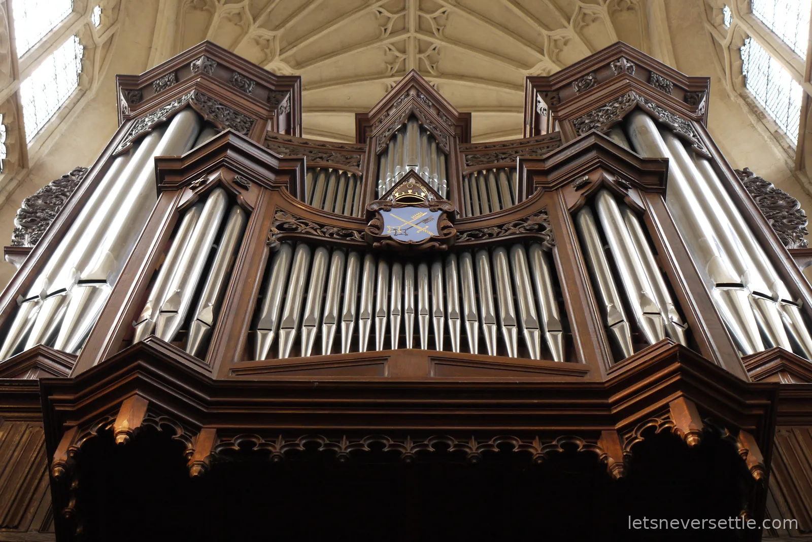 Silver organ pipes in a carved wooden case beneath a fan-vaulted stone ceiling