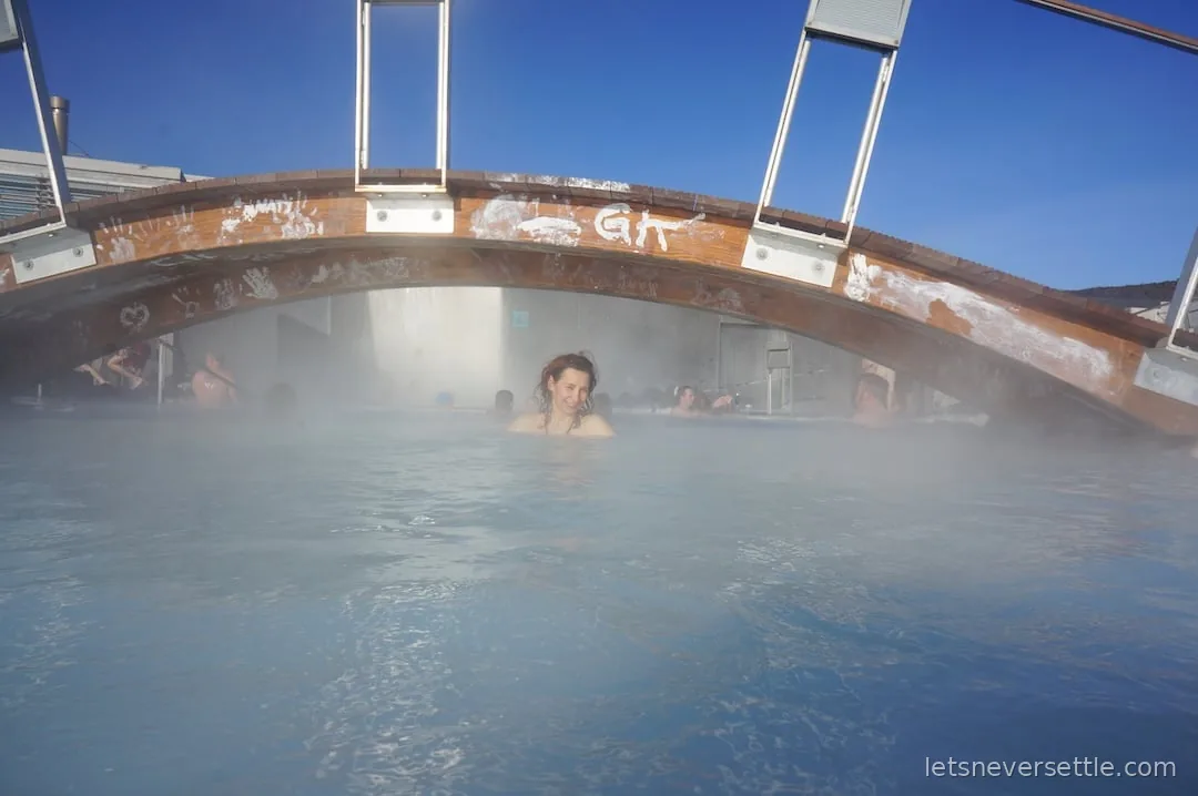 Inga in the water beneath the Blue Lagoon's wooden bridge, its beams covered in white silica handprints