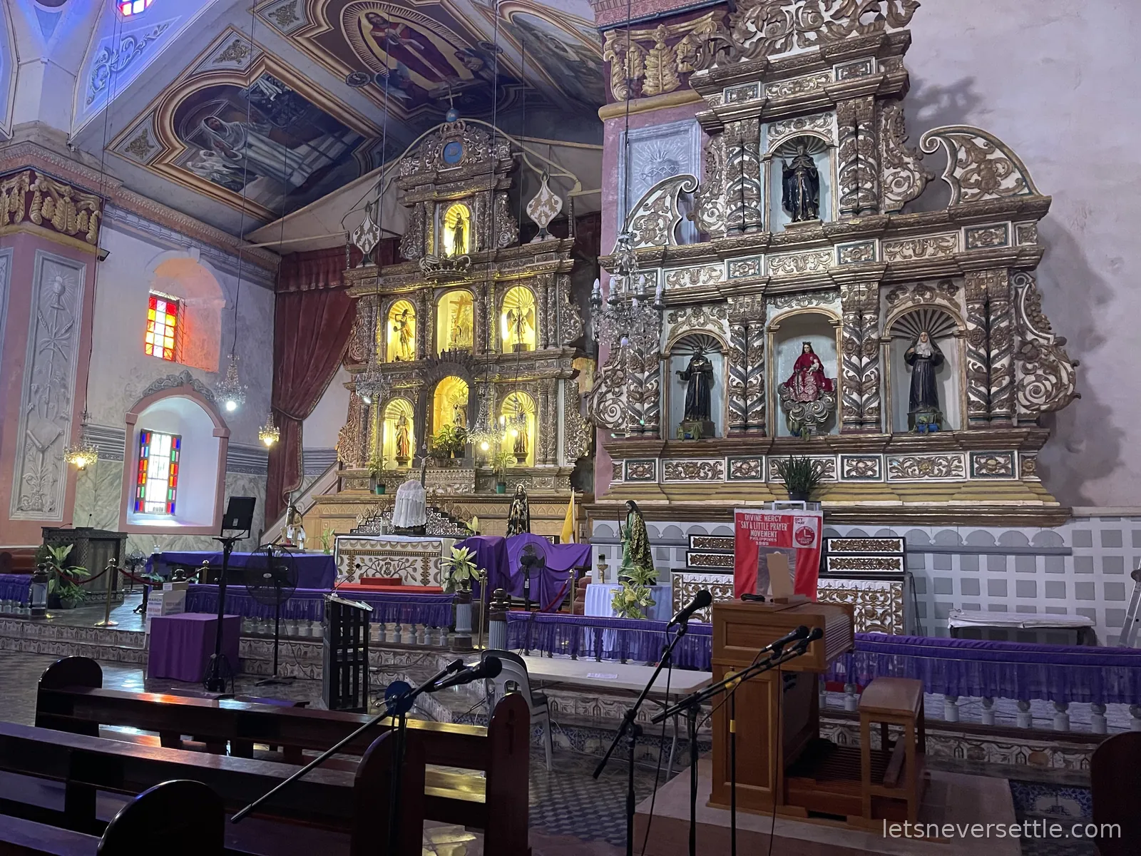 The silver and gilt retablo behind the altar of Baclayon church in Bohol, statues in niches and the altar draped in purple cloth for Lent