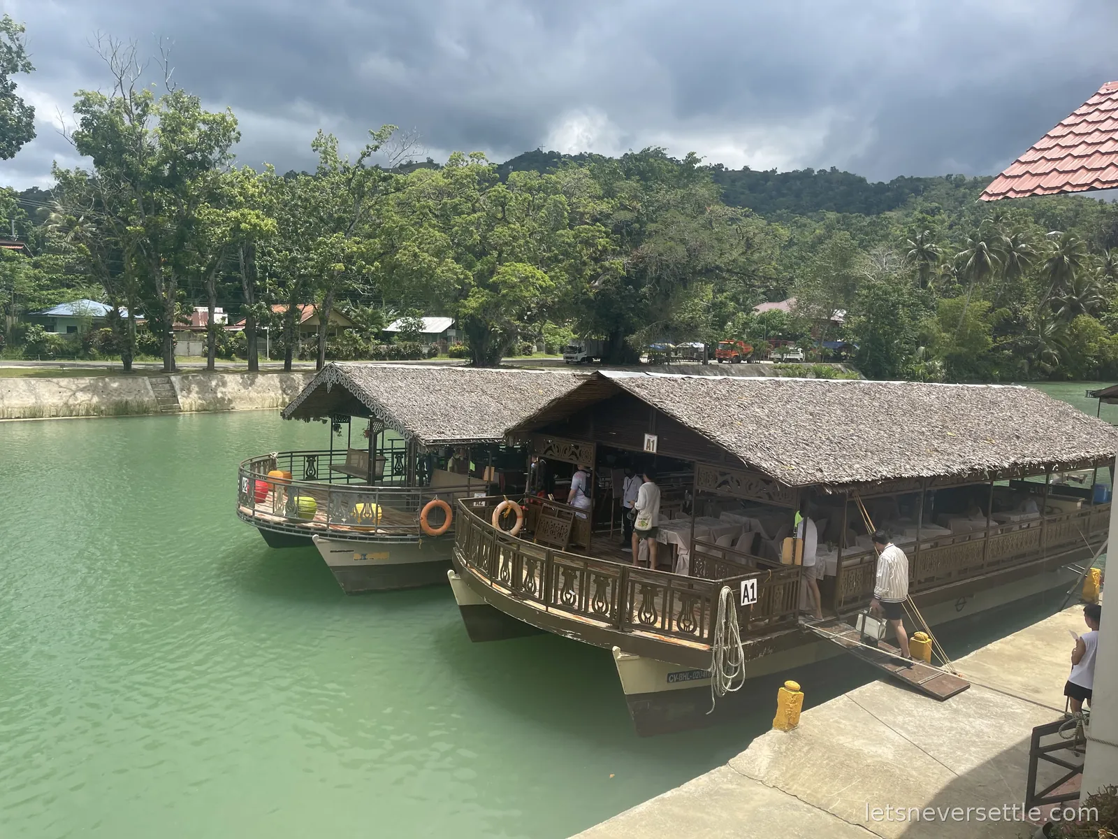 Two bamboo-roofed floating restaurants moored on the green Loboc River in Bohol, jungle rising on the far bank