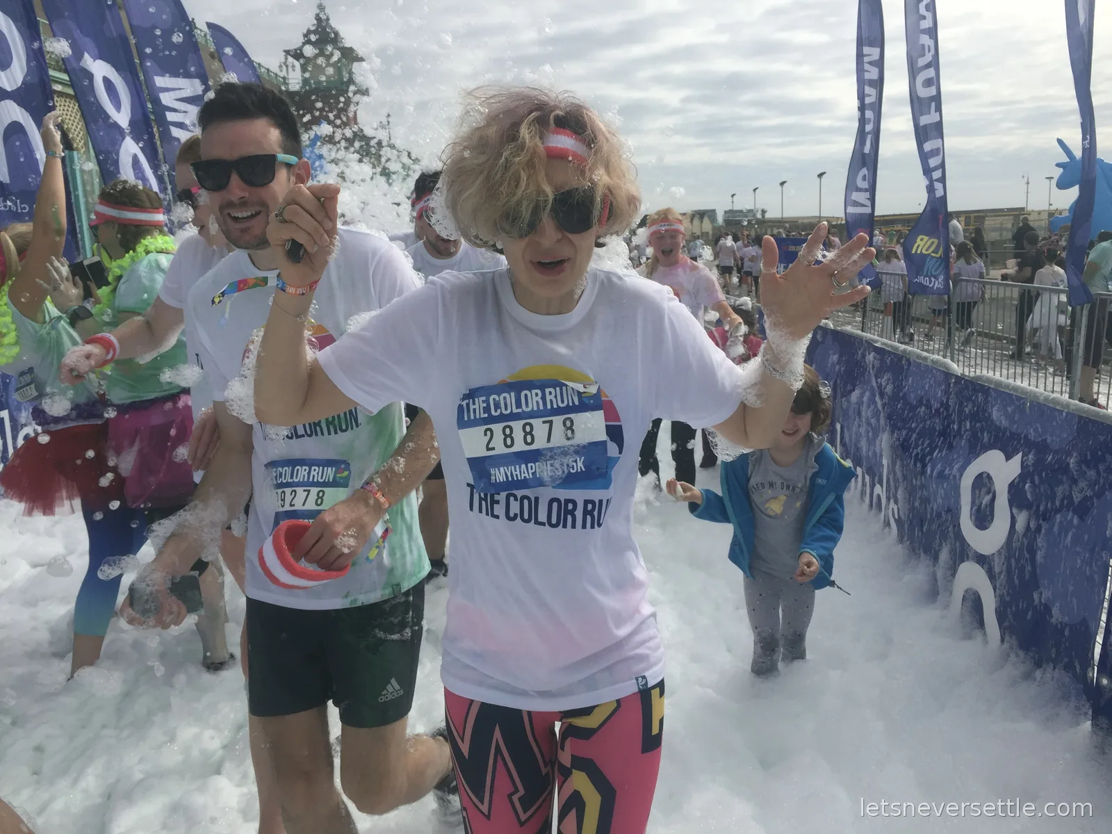 Inga and friends laughing through waist-deep foam in the finish zone of The Color Run on Brighton seafront