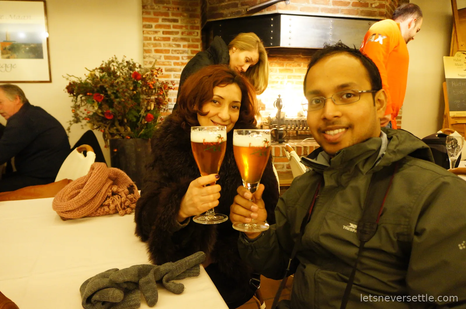 Toasting two glasses of Brugse Zot beer in front of an open fireplace at the De Halve Maan brewery in Bruges