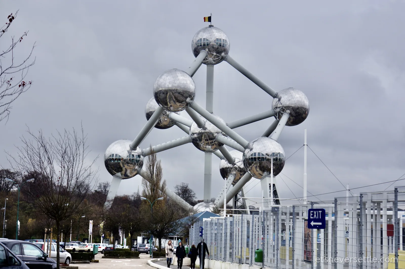 The Atomium in Brussels, nine giant steel spheres connected by tubes, under a heavy grey sky with a Belgian flag on top