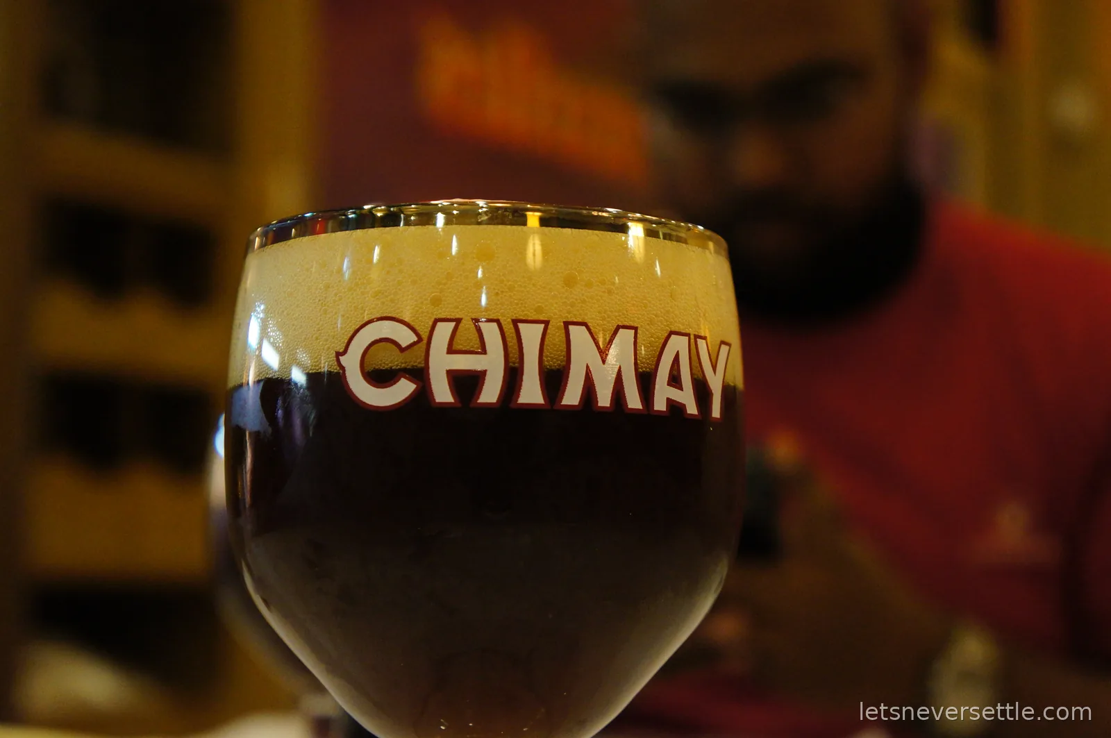 Close-up of a Chimay glass filled with dark Trappist beer under a thick cream-coloured head of foam