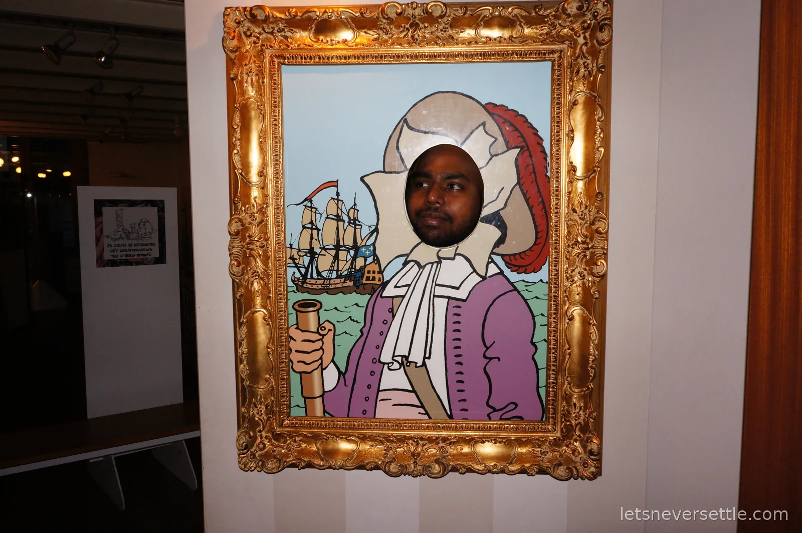 A man's face poking through the cutout of a comic-style portrait of a plumed nobleman in a gold frame, with a sailing ship painted behind