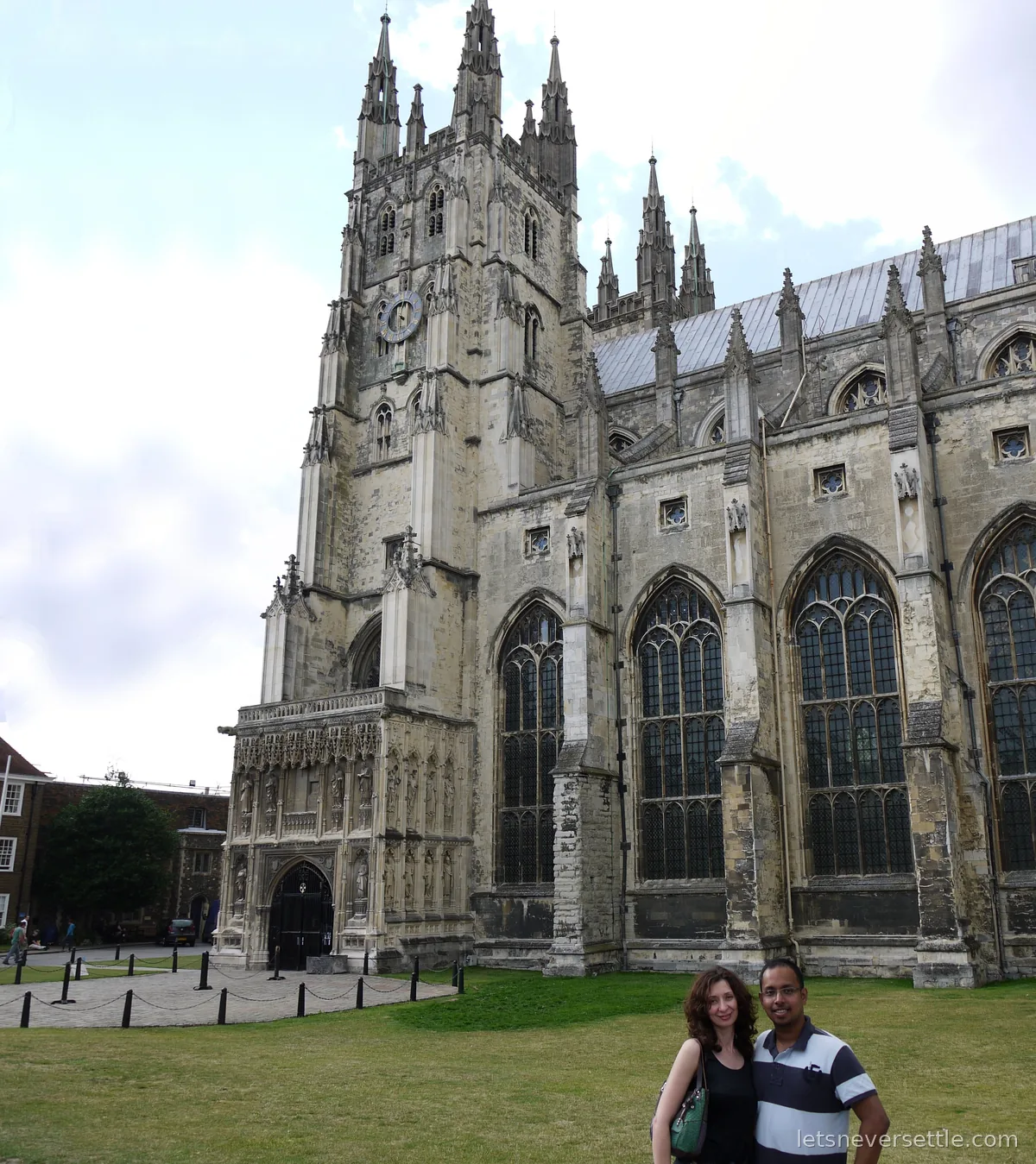 Inga and Dileep standing together on the lawn in front of Canterbury Cathedral, its tower rising behind them