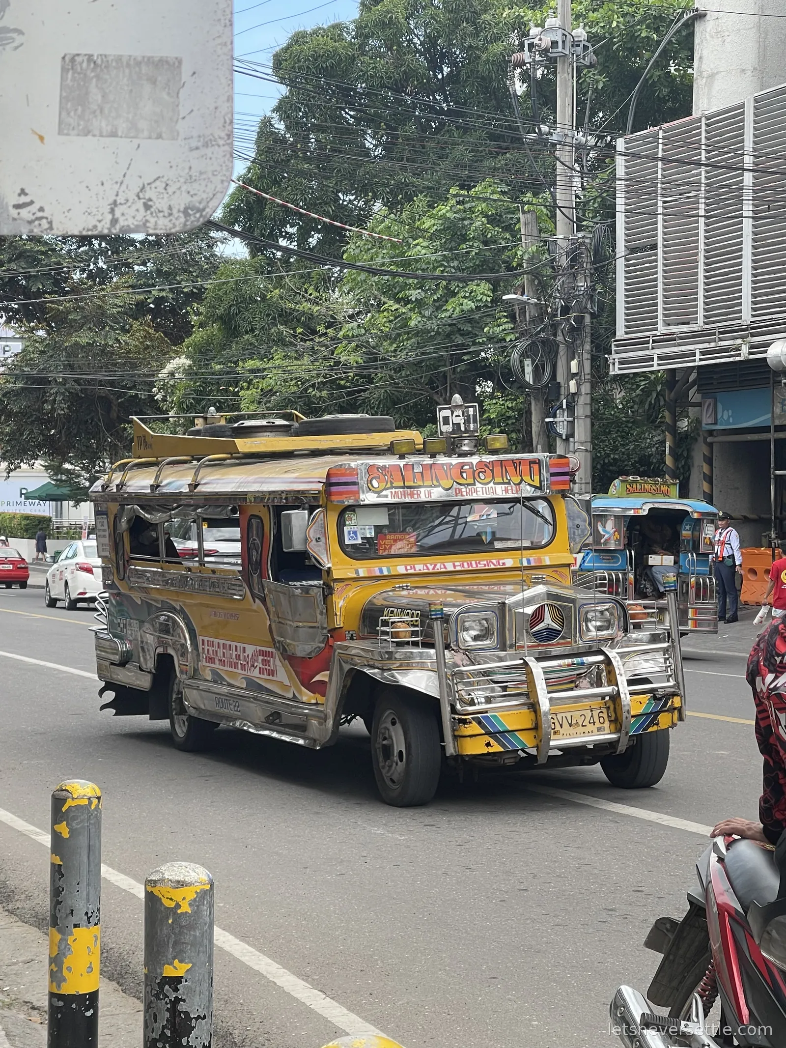A jeepney painted yellow and red with a chrome grille and hand-lettered route board waiting at the roadside in Cebu City