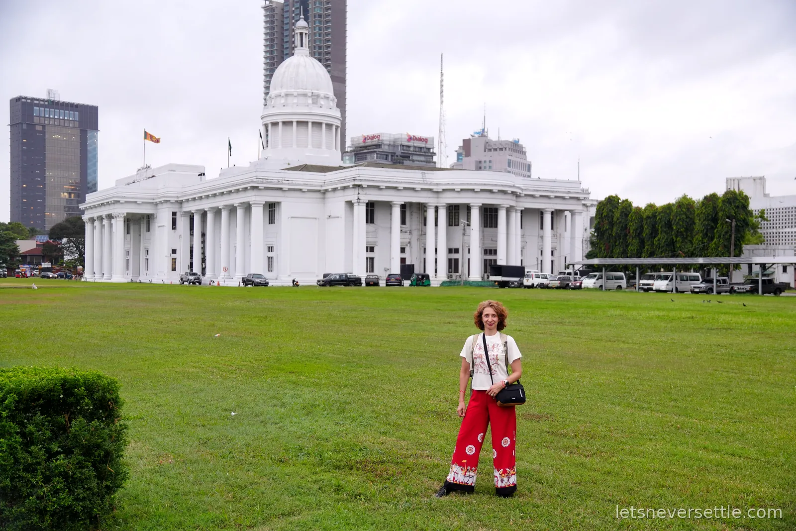 Inga in red patterned trousers on the park lawn in front of the white dome and colonnades of Colombo Town Hall