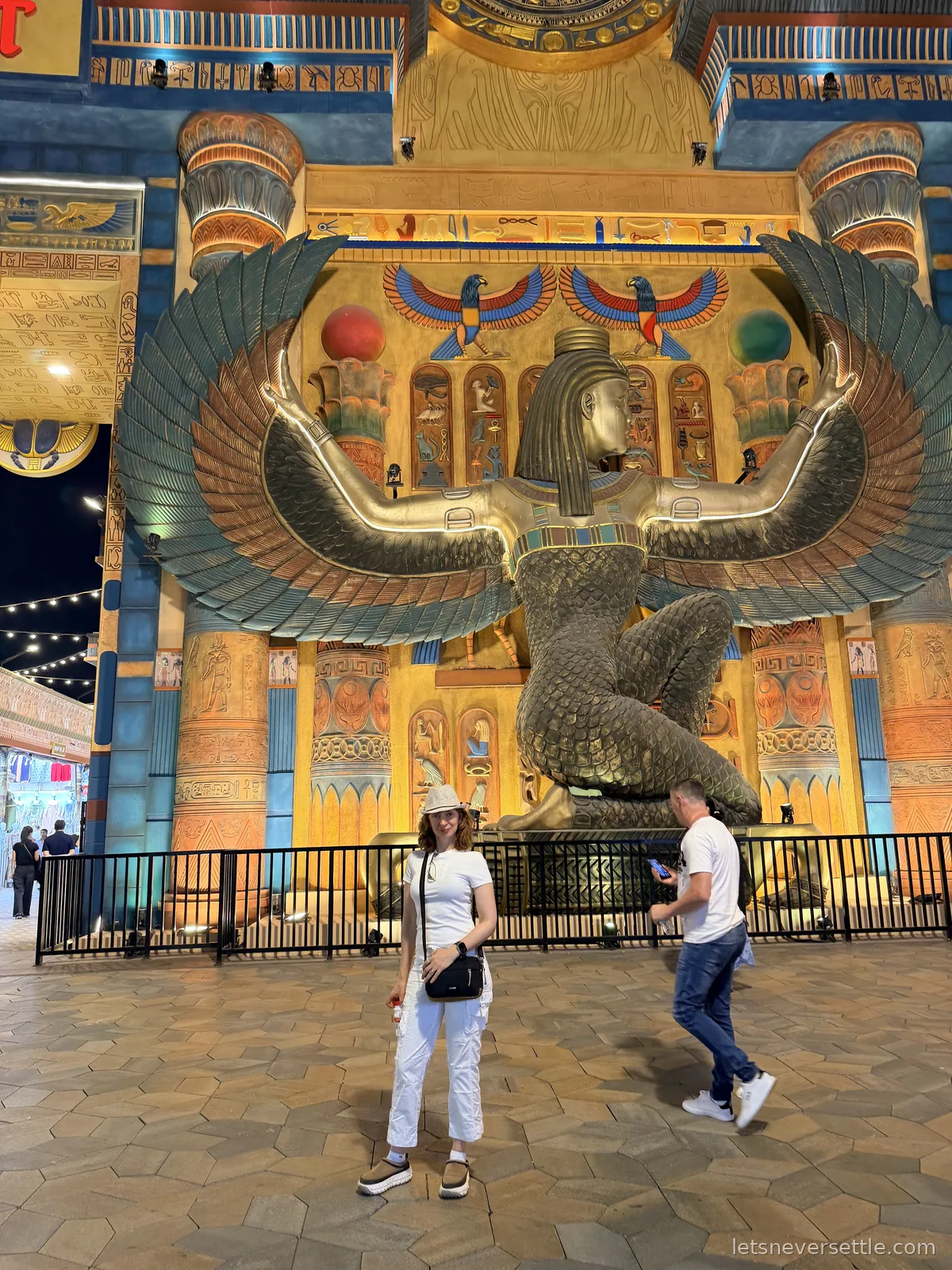 Inga standing in front of the Egypt pavilion at Global Village, a huge gold winged statue and painted hieroglyphs lit up behind her