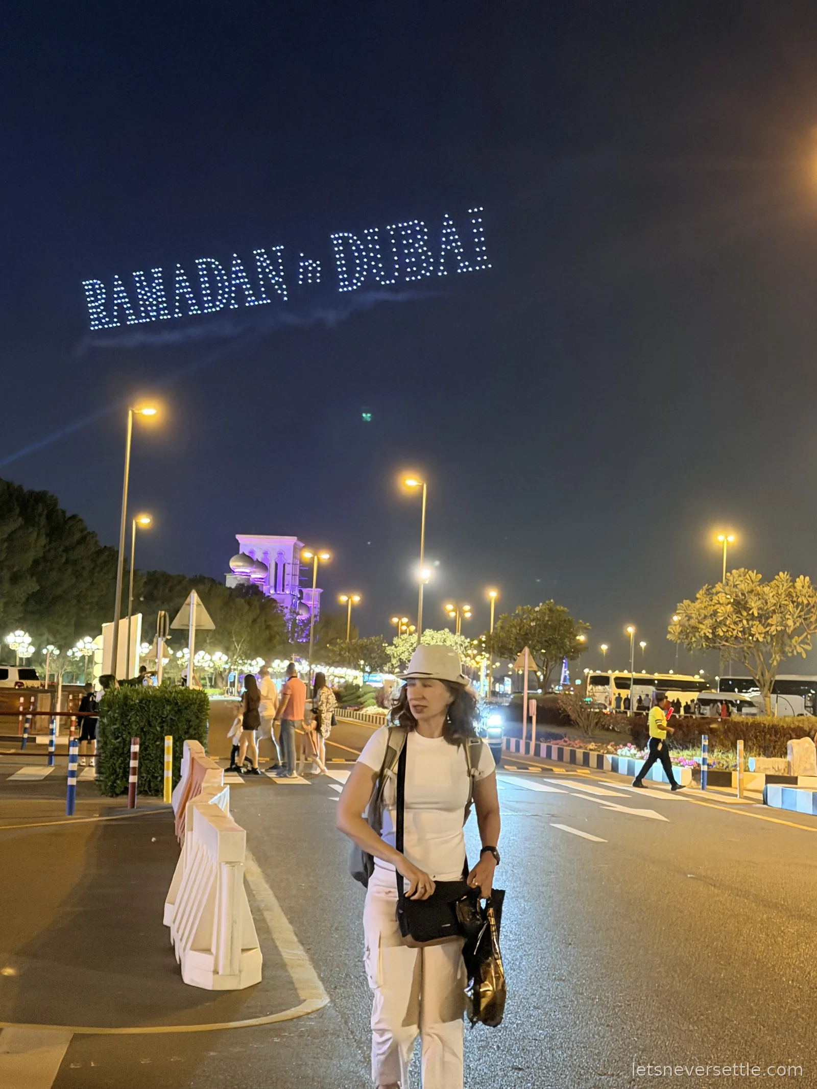 A drone show spelling out a glowing Ramadan greeting in the night sky above Global Village in Dubai, with Inga in the foreground