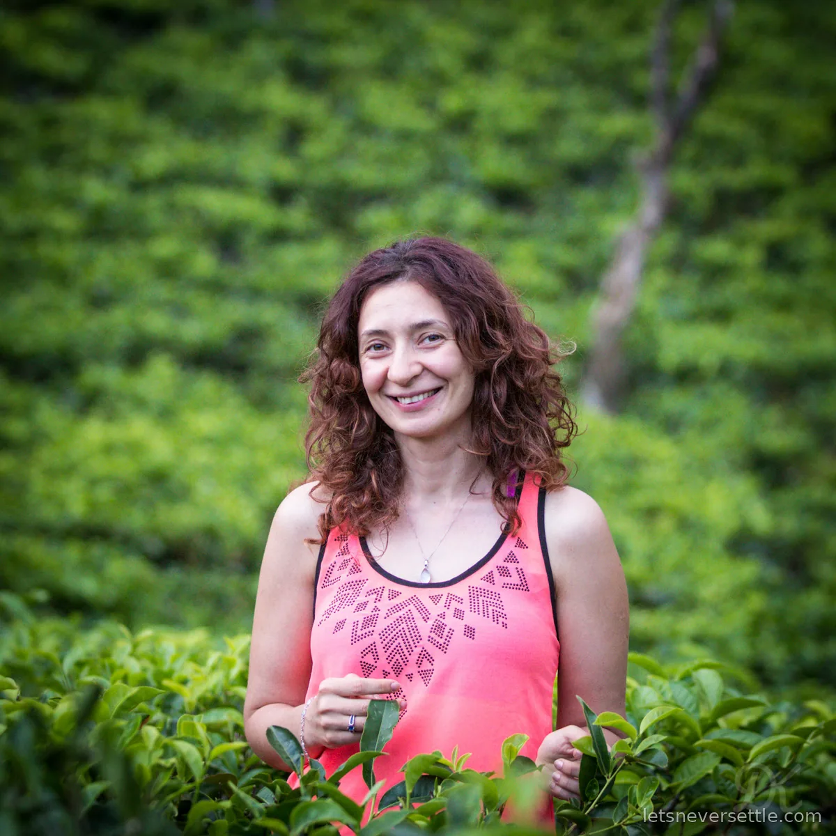 Inga smiling waist deep in bright green tea bushes on a hillside