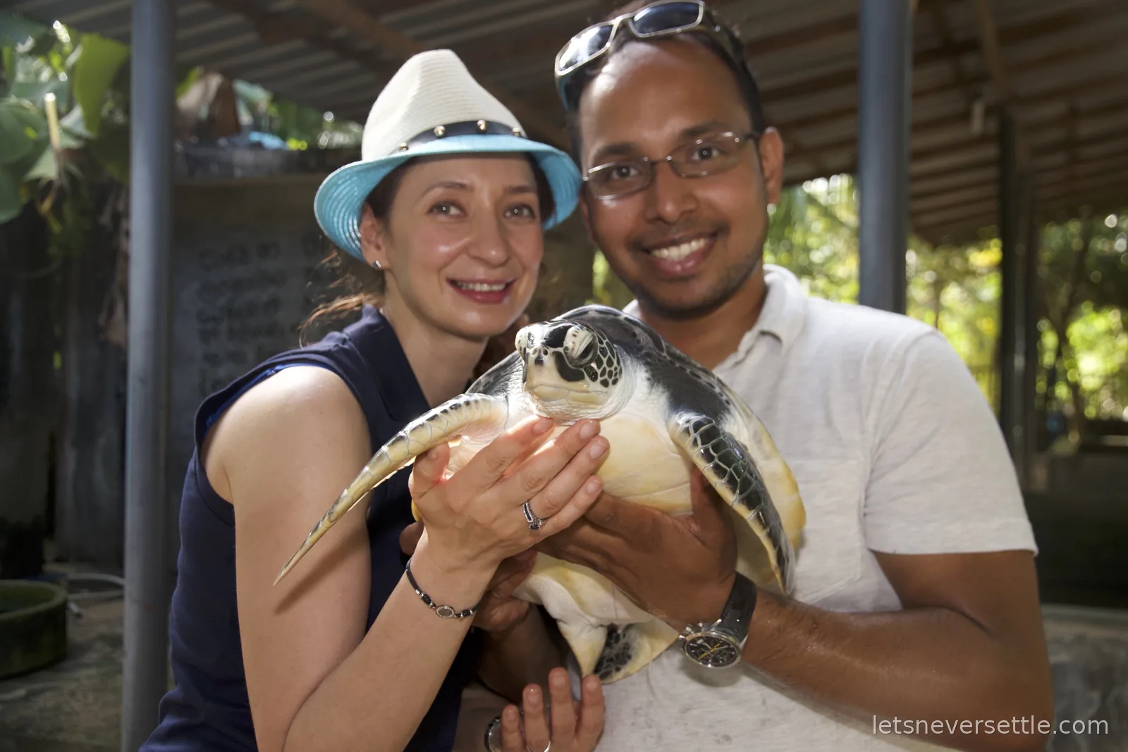 Inga and Dileep together holding a large green turtle between them at the hatchery