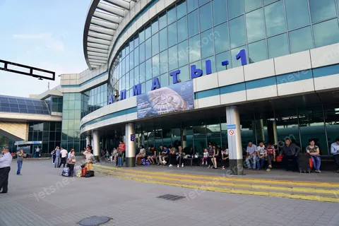 The blue glass frontage of Almaty railway station with passengers waiting outside