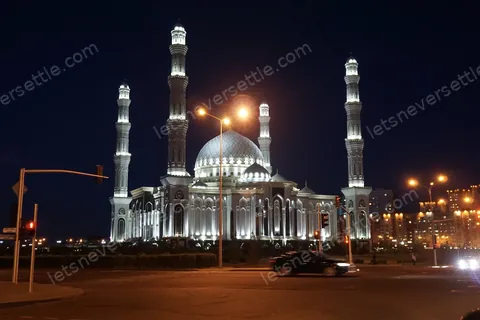 A domed mosque in Astana floodlit at night, its four minarets picked out against the sky