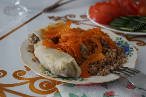 A plate of shredded carrot salad beside a filled pastry on patterned crockery