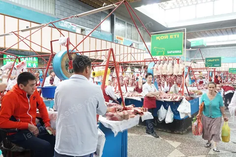 The meat hall of the Green Bazaar in Almaty, butchers working behind long steel counters