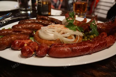 A plate of grilled sausages with onions and herbs