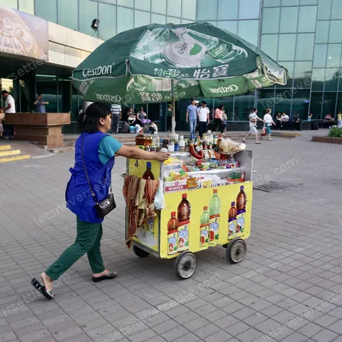 A vendor pushing a small ice cream cart across a square in Kazakhstan