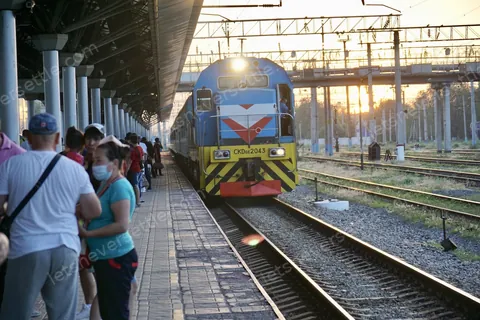 Passengers standing on the platform beside a train at sunset