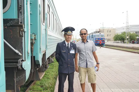 Dileep beside the carriage with the train conductor in uniform and peaked cap
