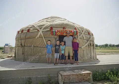 Four children standing in front of a yurt out on the steppe