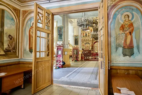 Inside Zenkov Cathedral in Almaty, painted saints on the wooden walls and a chandelier hanging above