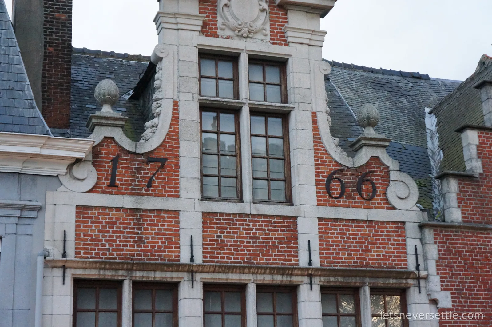 Red brick step gable in Ghent with the year 1766 mounted in dark numerals either side of an arched window