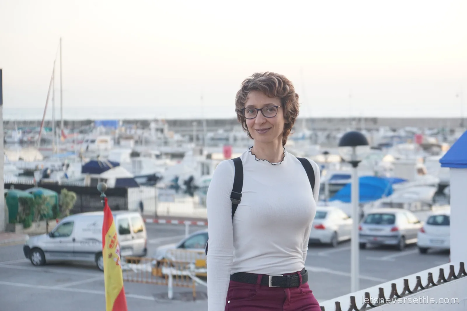 Inga with a cold drink on a white rooftop terrace in Estepona, white houses and pine-covered hills running down to a bright blue sea