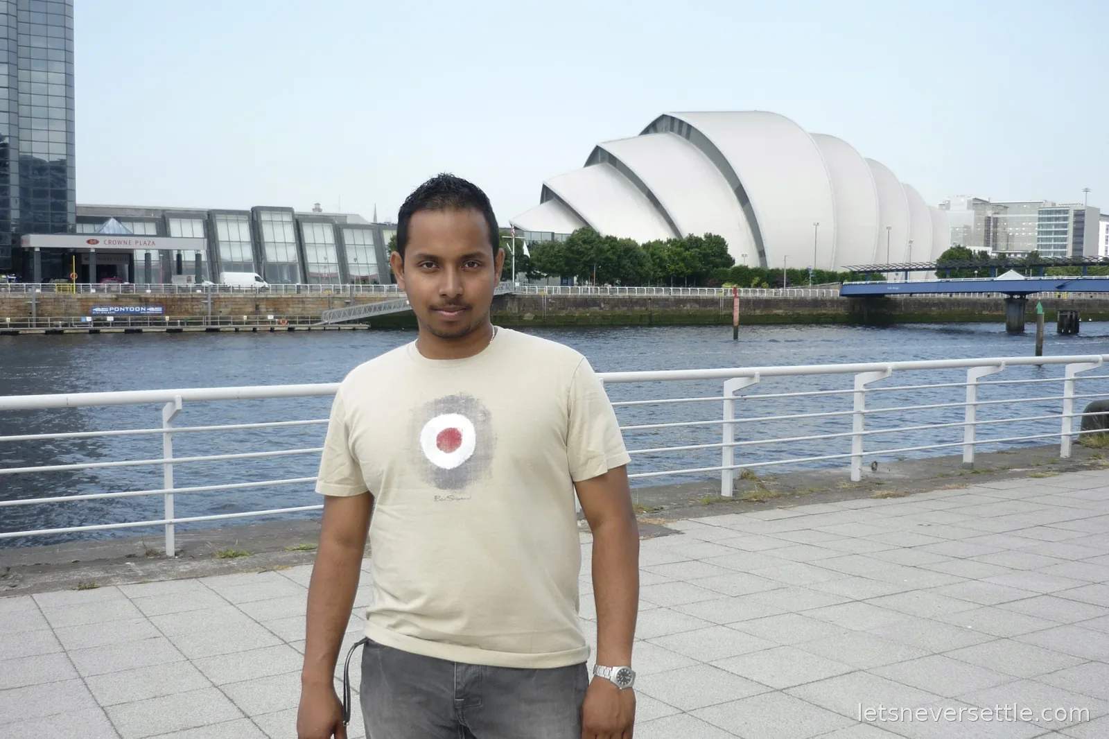Dileep on the riverside walkway with the curved silver shells of the Clyde Auditorium, known as the Armadillo, across the water