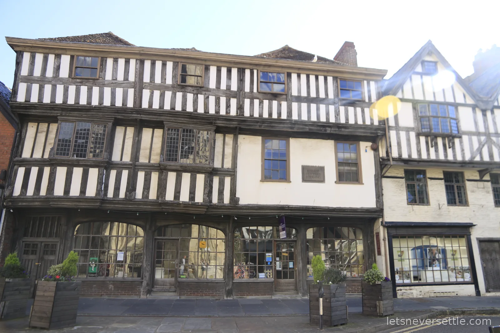 Three-gabled timber-framed Tudor houses in Gloucester with leaded windows and a wall plaque reading Bishop Hooper's Lodging