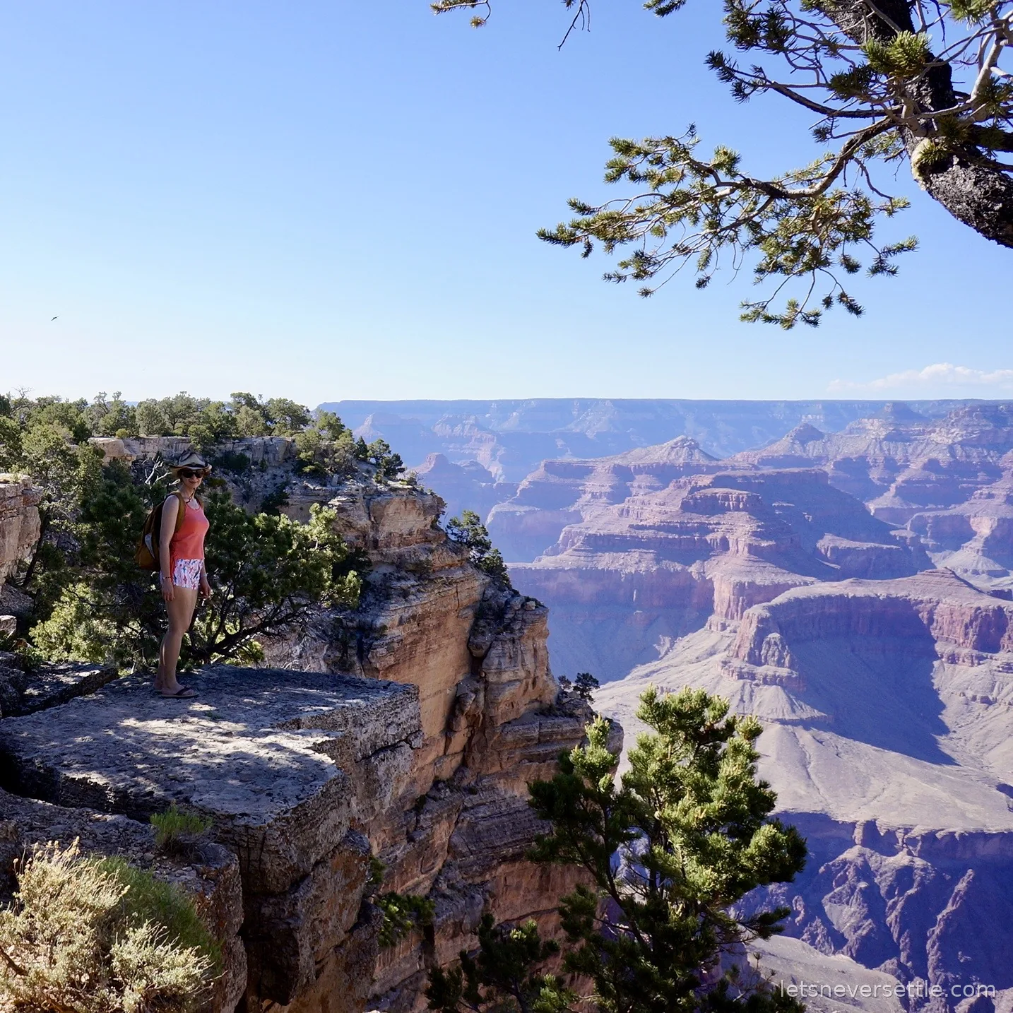 Inga standing on a rock outcrop jutting over the Grand Canyon, canyon walls glowing behind her