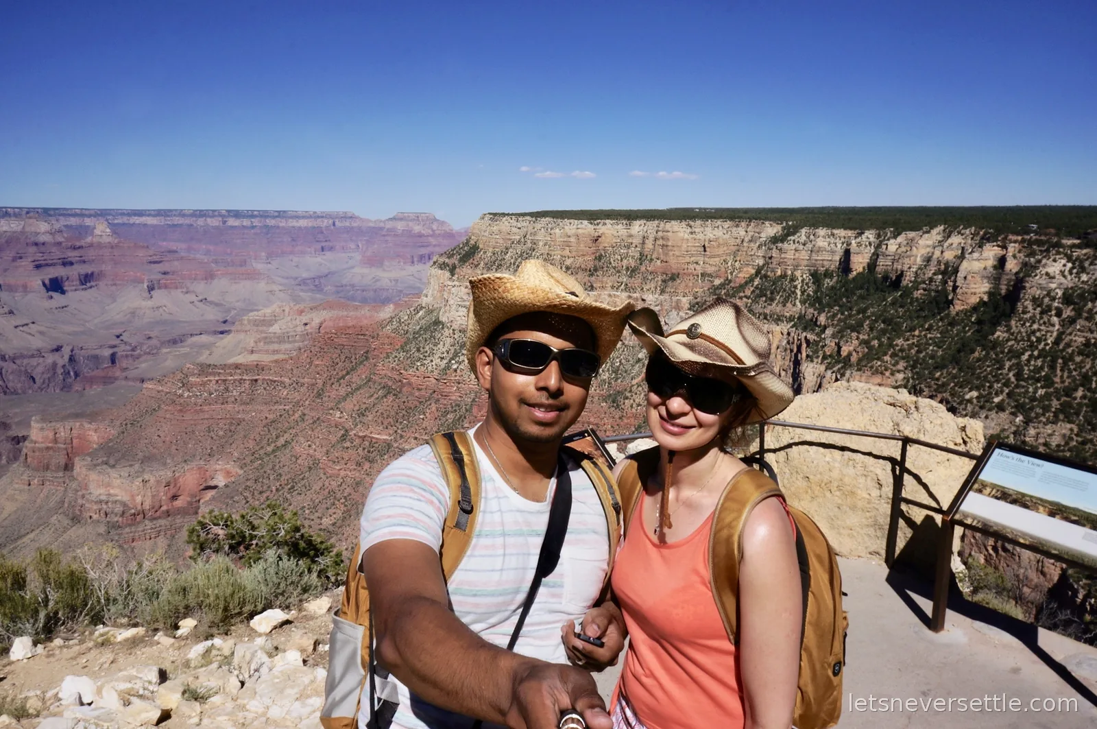 Selfie of Inga and Dileep at a railed overlook with an interpretive sign and the canyon behind