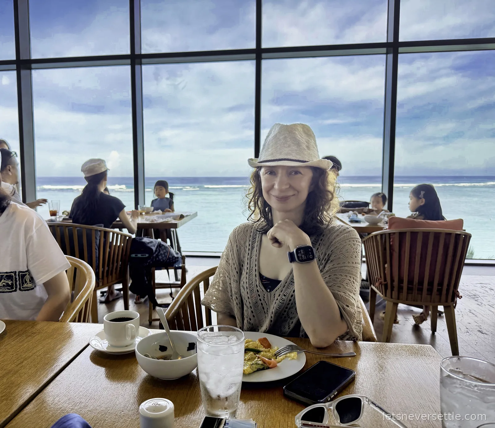 Inga at a breakfast table in a restaurant with floor-to-ceiling windows, the reef and open Pacific filling the view behind her