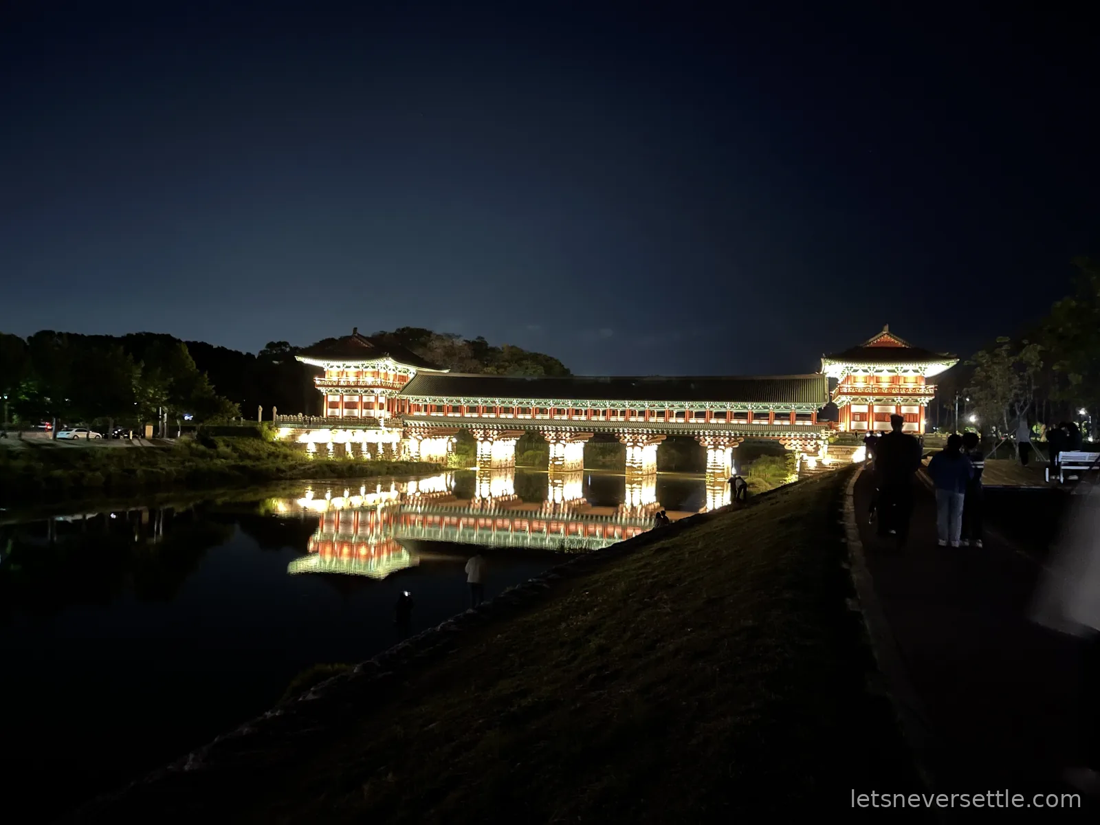 Woljeonggyo, a covered wooden bridge in Gyeongju with pavilion towers at each end, lit up at night and reflected in the river