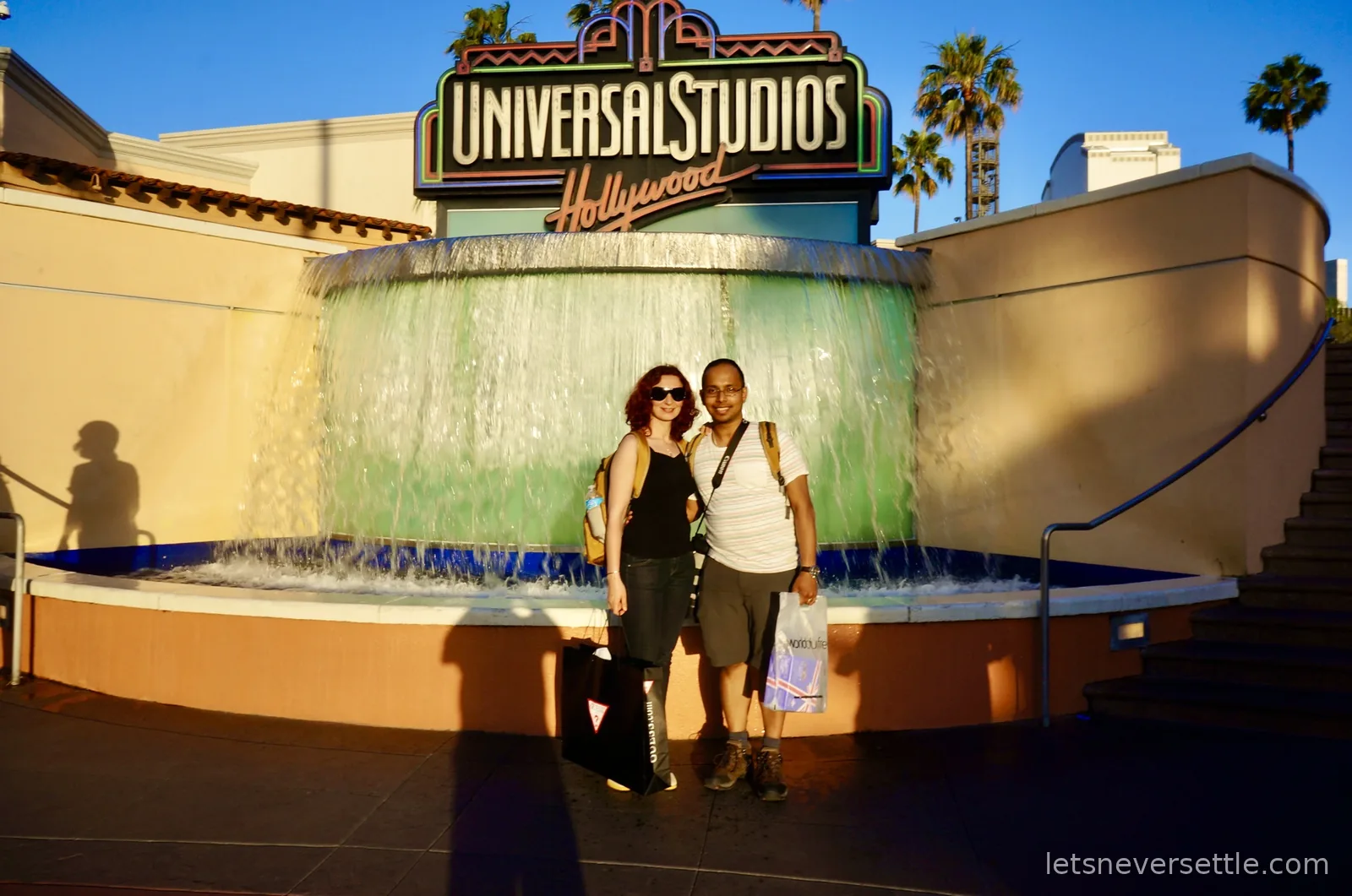 Inga and Dileep in front of the Universal Studios Hollywood entrance fountain in golden evening light