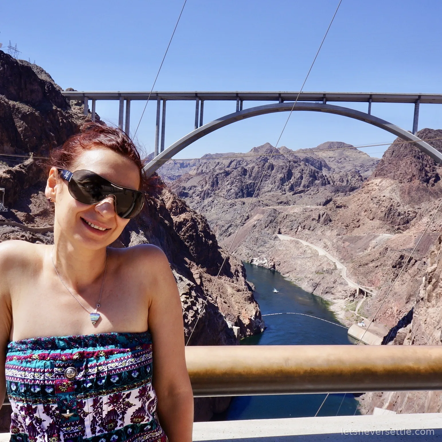 Inga at a railing with the concrete arch of the bypass bridge spanning the Colorado River gorge behind