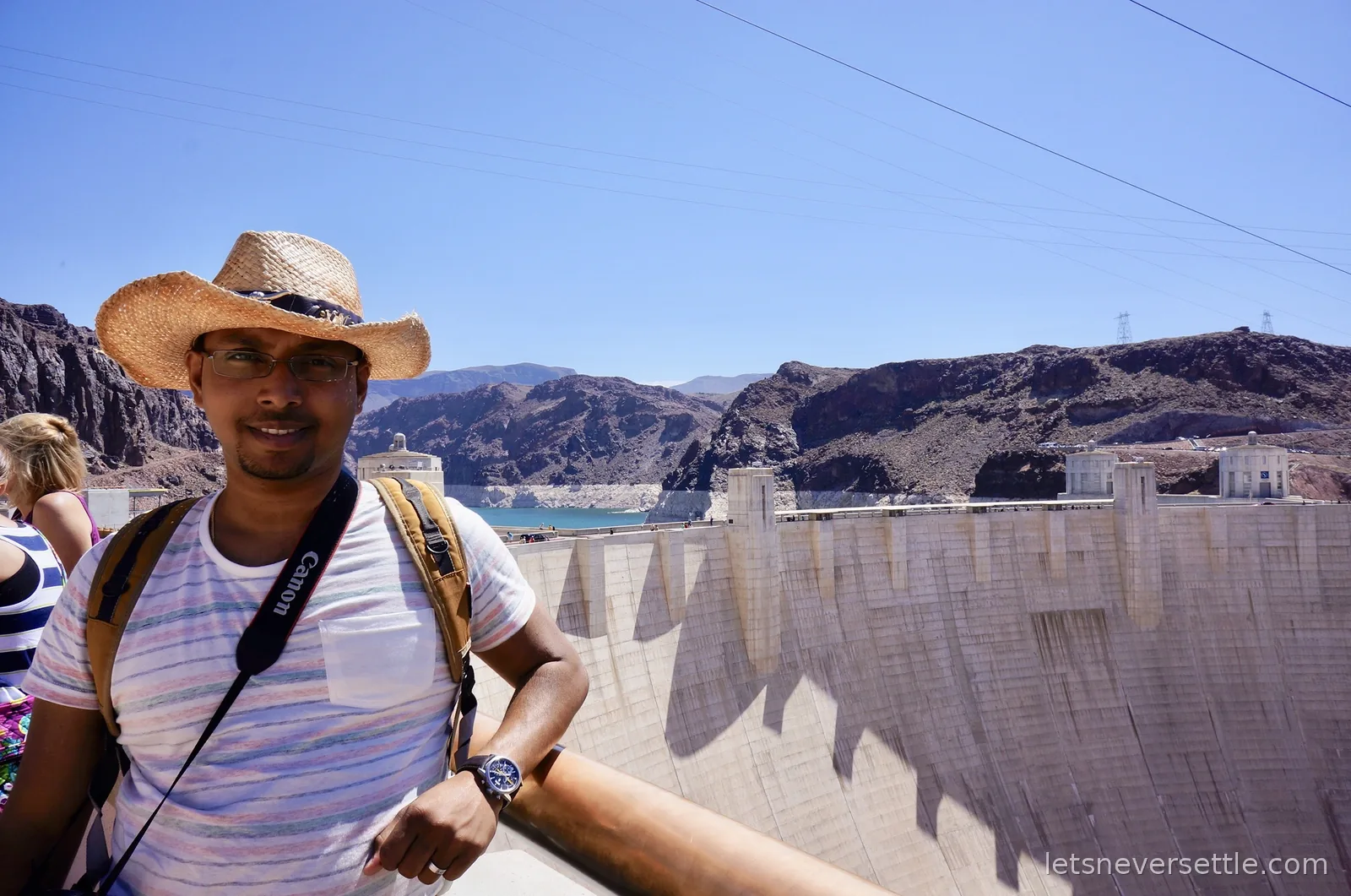 Dileep standing above the sweeping concrete face of Hoover Dam with the river far below