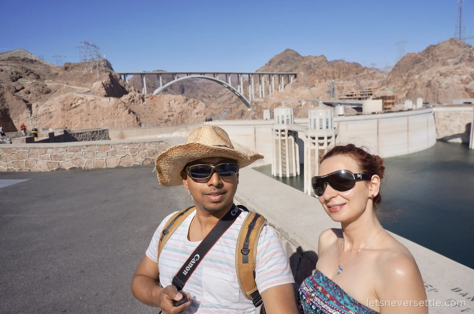 Selfie of Inga and Dileep with the curved concrete face of Hoover Dam behind them
