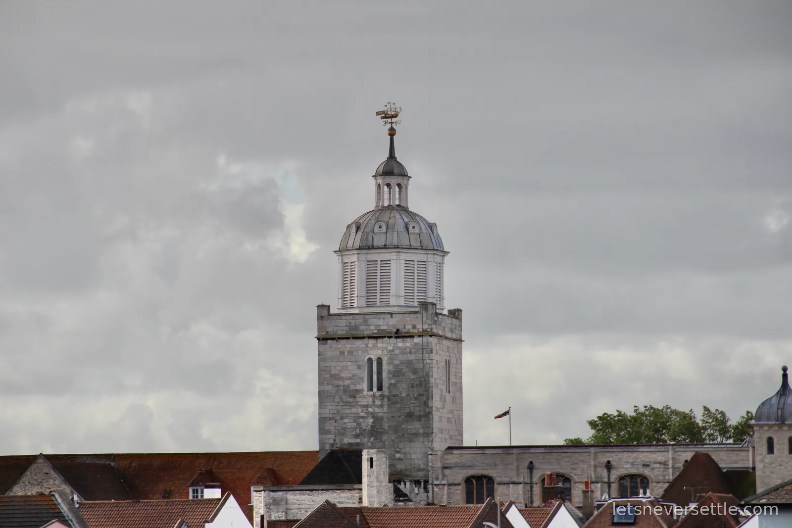 The cupola-topped tower of Portsmouth Cathedral rising over rooftops under heavy grey clouds