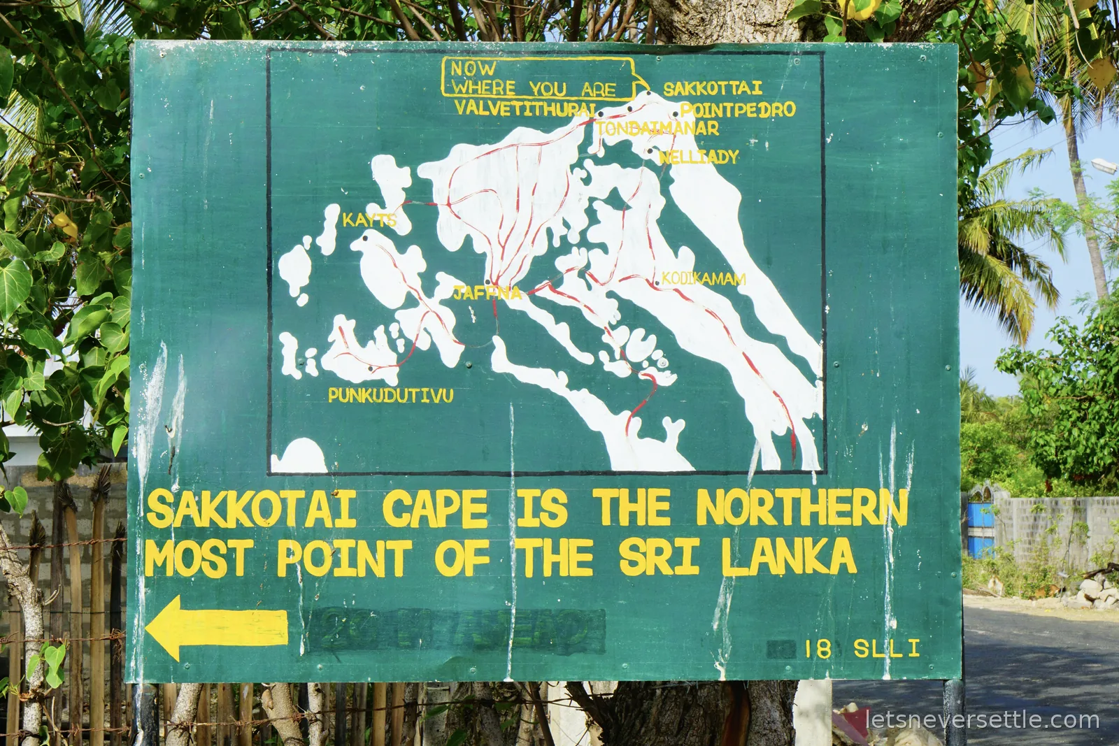 A weathered green road sign with a hand-painted yellow map of the Jaffna peninsula, marked Now where you are, above the words Sakkotai Cape is the northern most point of the Sri Lanka
