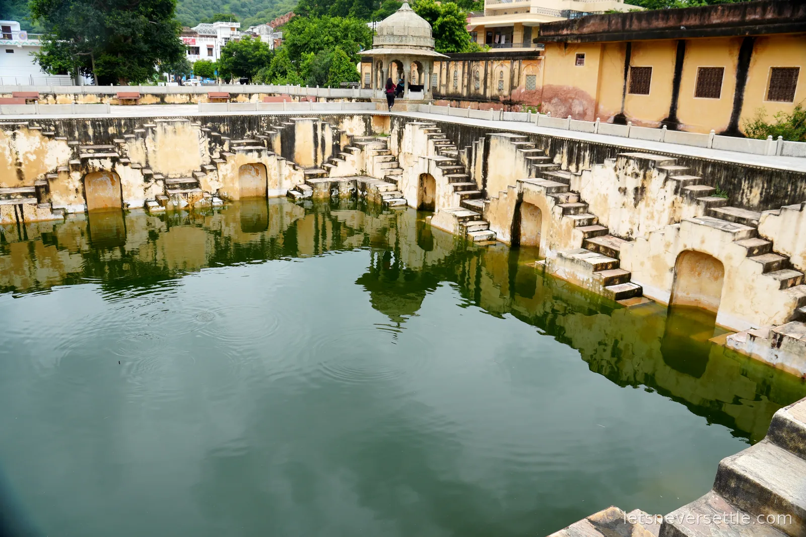 The full sweep of Panna Meena ka Kund stepwell, zigzag staircases descending on every side to green water, a domed pavilion on the rim