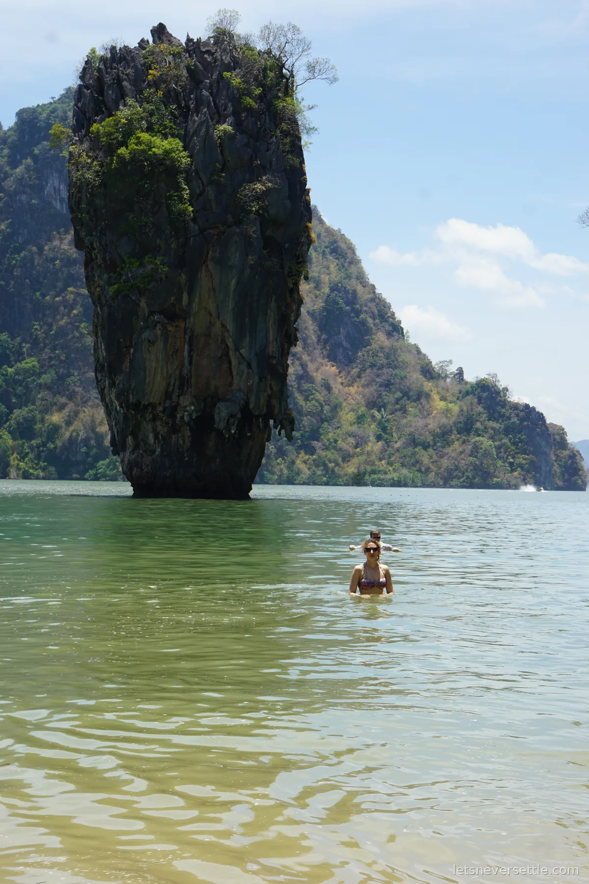Inga swimming in shallow jade-green water in front of Ko Tapu, the narrow limestone stack that rises straight out of the bay at James Bond Island
