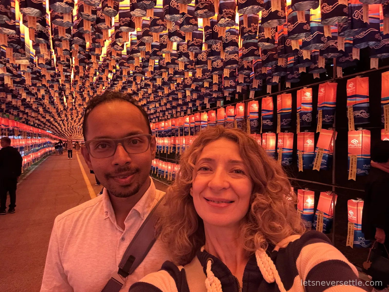 Selfie of Inga and Dileep inside a tunnel completely lined with thousands of small glowing festival lanterns