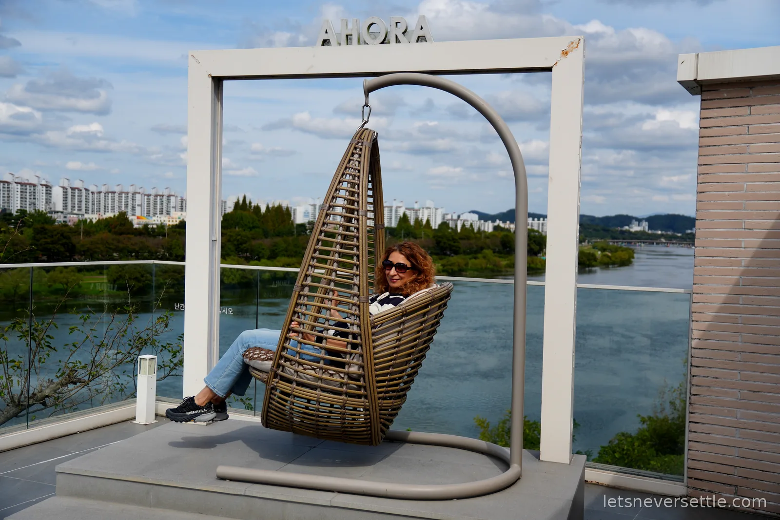 Inga relaxing in a rattan hanging egg chair on a cafe terrace overlooking the Nam River in Jinju
